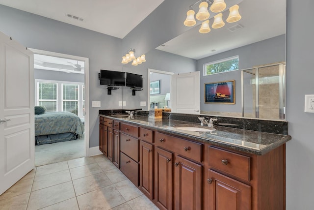 ensuite bathroom featuring tile patterned floors, a chandelier, a shower stall, double vanity, and baseboards