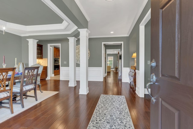 entryway featuring ornate columns, dark wood-style floors, a wainscoted wall, crown molding, and recessed lighting