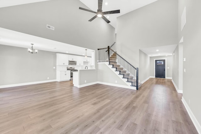614 Woodrush Dr, Clarksville, TN 37040 - unfurnished living room featuring a towering ceiling, a chandelier, stairway, light wood finished floors, and recessed lighting