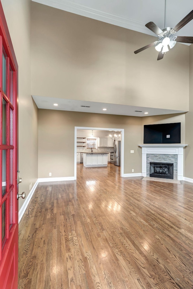 1317 Sam Houston Ave, Murfreesboro, TN 37129 - unfurnished living room with a high ceiling, a fireplace with flush hearth, a ceiling fan, baseboards, and wood finished floors