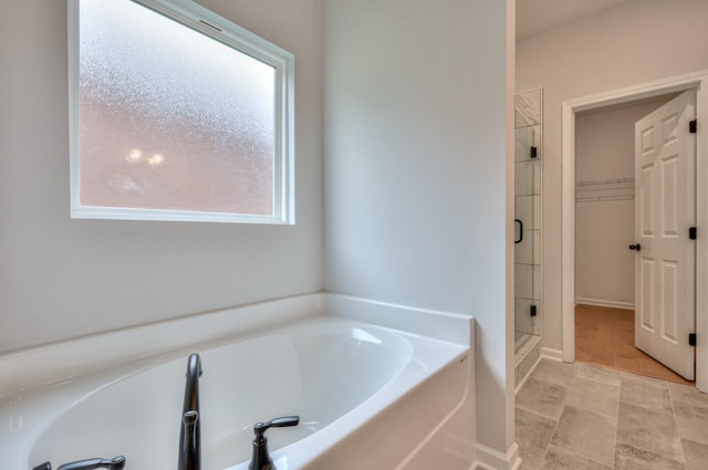 bathroom with a stall shower, a bath, tile patterned floors, and a walk in closet