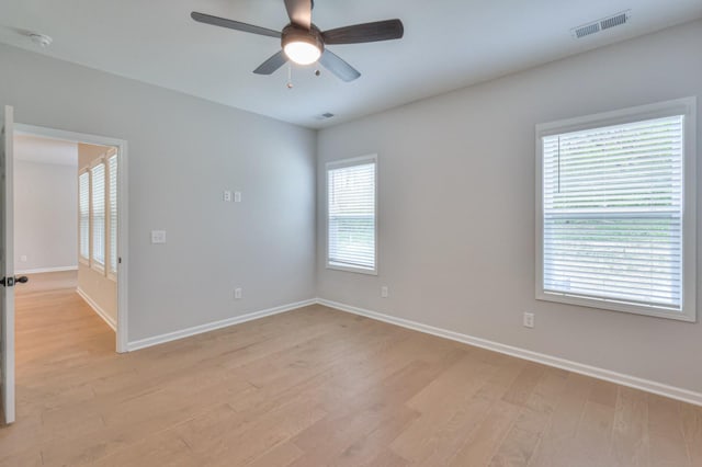 spare room featuring light wood finished floors, baseboards, a ceiling fan, and a smoke detector