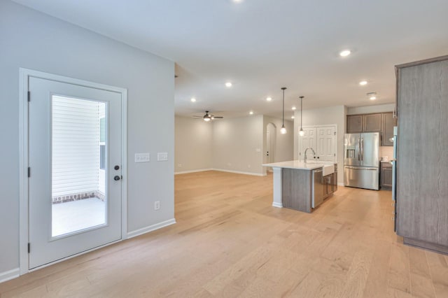 kitchen featuring stainless steel refrigerator with ice dispenser, open floor plan, light wood finished floors, recessed lighting, and light countertops