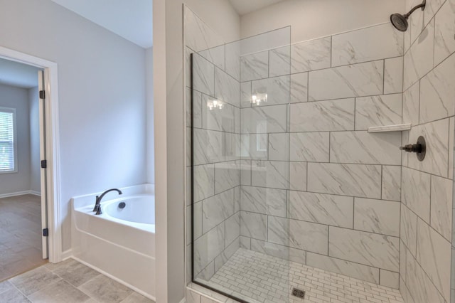 bathroom with tiled shower, a bath, and baseboards