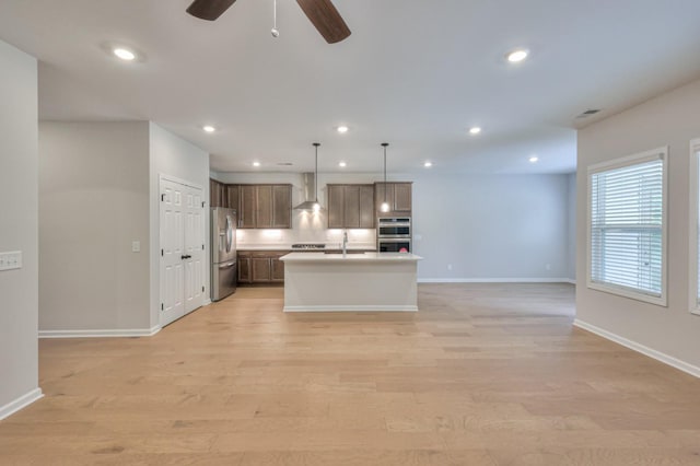 kitchen with appliances with stainless steel finishes, wall chimney exhaust hood, open floor plan, baseboards, and recessed lighting