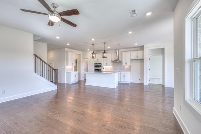 unfurnished living room featuring baseboards, dark wood-style floors, a ceiling fan, stairs, and recessed lighting