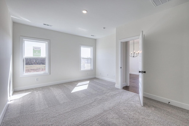 unfurnished room featuring carpet floors, baseboards, and a chandelier