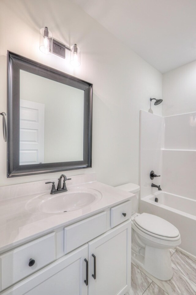 bathroom with vanity, toilet, marble look tile flooring, and  shower combination