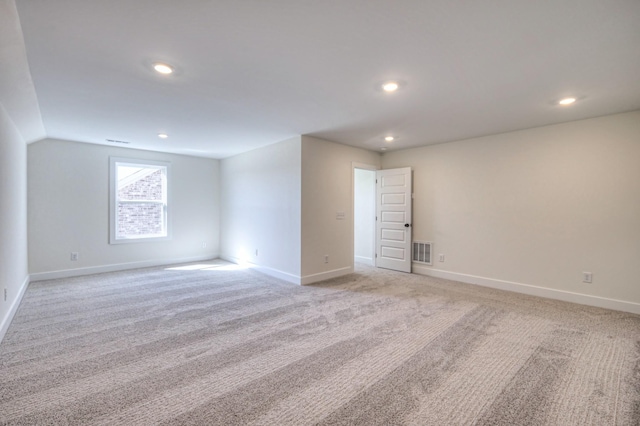 spare room featuring light carpet, recessed lighting, baseboards, and lofted ceiling