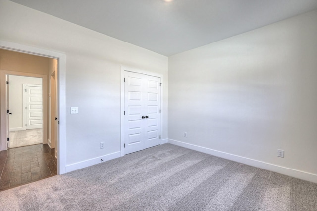unfurnished room with baseboards and dark colored carpet
