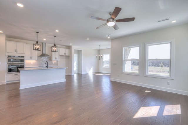 unfurnished living room with a sink, baseboards, a chandelier, recessed lighting, and dark wood-type flooring