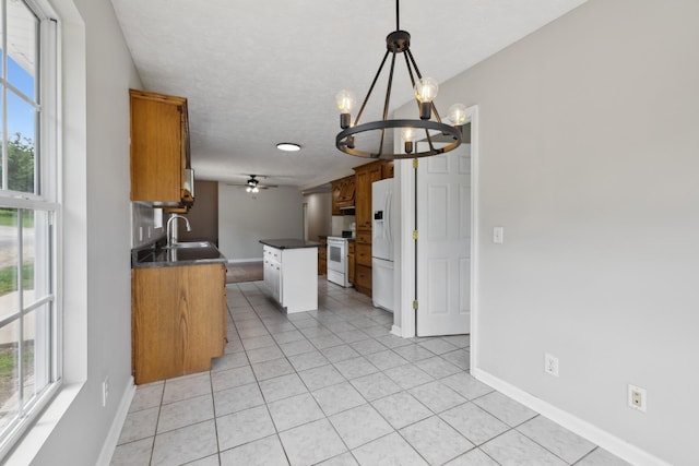 kitchen featuring dark countertops, white appliances, a chandelier, baseboards, and plenty of natural light