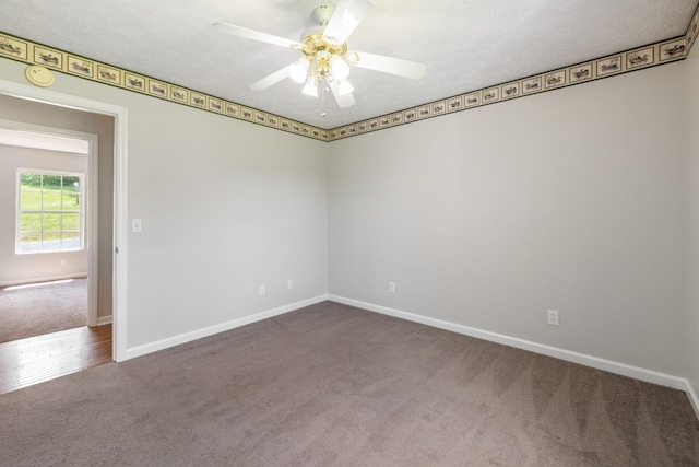 unfurnished room featuring dark carpet, a ceiling fan, baseboards, and a smoke detector