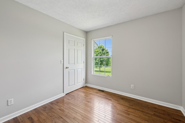 unfurnished room featuring baseboards, hardwood / wood-style flooring, and a textured ceiling