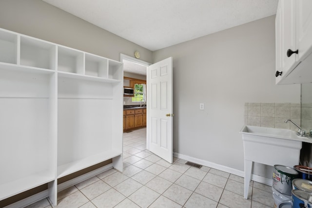 mudroom featuring light tile patterned flooring, a sink, and baseboards