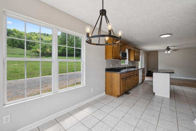 kitchen featuring dark countertops, baseboards, stainless steel microwave, a chandelier, and a textured ceiling
