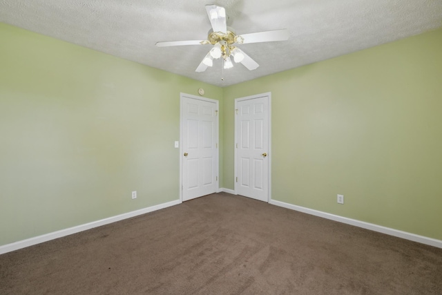 unfurnished room featuring baseboards, dark colored carpet, a ceiling fan, and a textured ceiling
