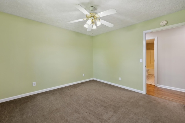 carpeted empty room featuring a ceiling fan, baseboards, a smoke detector, and a textured ceiling