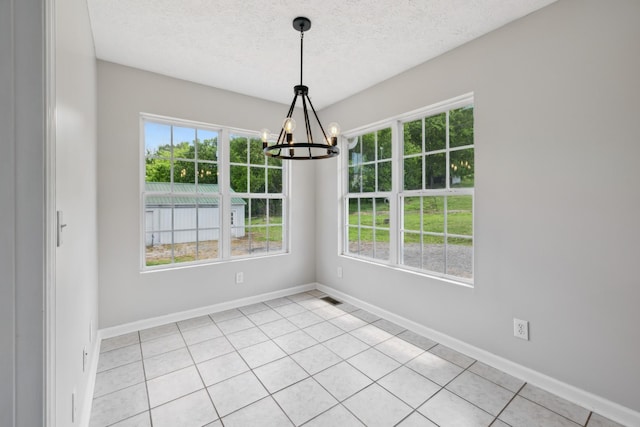 unfurnished dining area with a chandelier, a textured ceiling, baseboards, and light tile patterned floors
