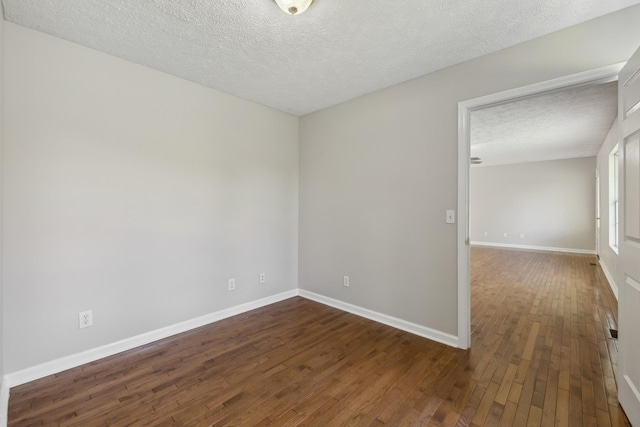 spare room featuring dark wood finished floors, a textured ceiling, and baseboards