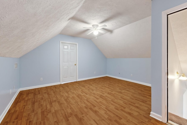 additional living space with wood finished floors, ceiling fan, a textured ceiling, baseboards, and vaulted ceiling