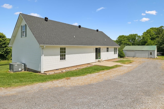 back of house featuring an outdoor structure, central air condition unit, a shingled roof, and a garage