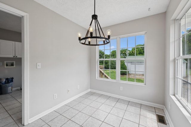 unfurnished dining area featuring plenty of natural light, a chandelier, baseboards, and a textured ceiling