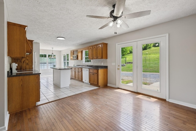 kitchen featuring white dishwasher, brown cabinets, dark countertops, light wood-type flooring, and a ceiling fan