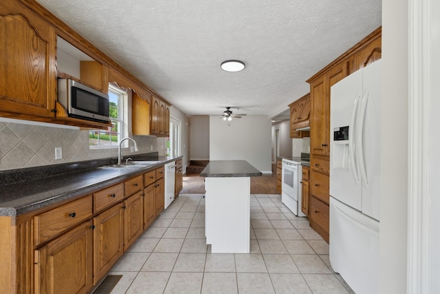 kitchen with white appliances, a sink, backsplash, dark countertops, and brown cabinetry