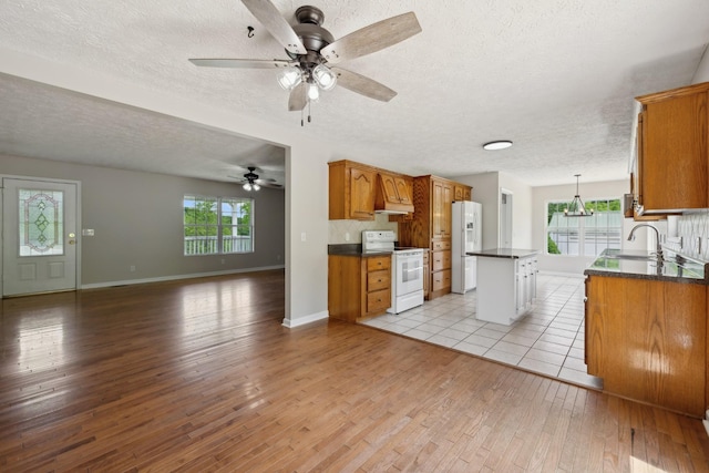kitchen with white appliances, dark countertops, ceiling fan, open floor plan, and light wood-style floors