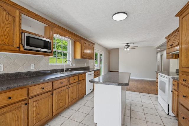 kitchen with white appliances, a sink, tasteful backsplash, a ceiling fan, and light tile patterned floors