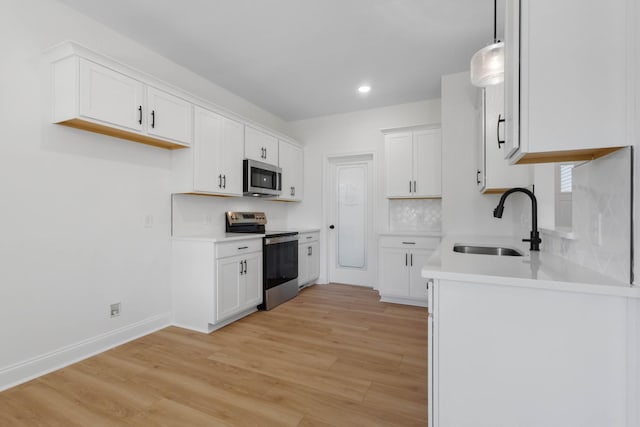 2214 S Hinton Rd, Southside, TN 37171 - kitchen with appliances with stainless steel finishes, a sink, light wood-style floors, decorative backsplash, and white cabinetry