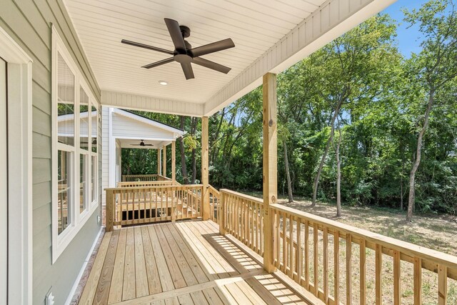 deck featuring ceiling fan and view of wooded area