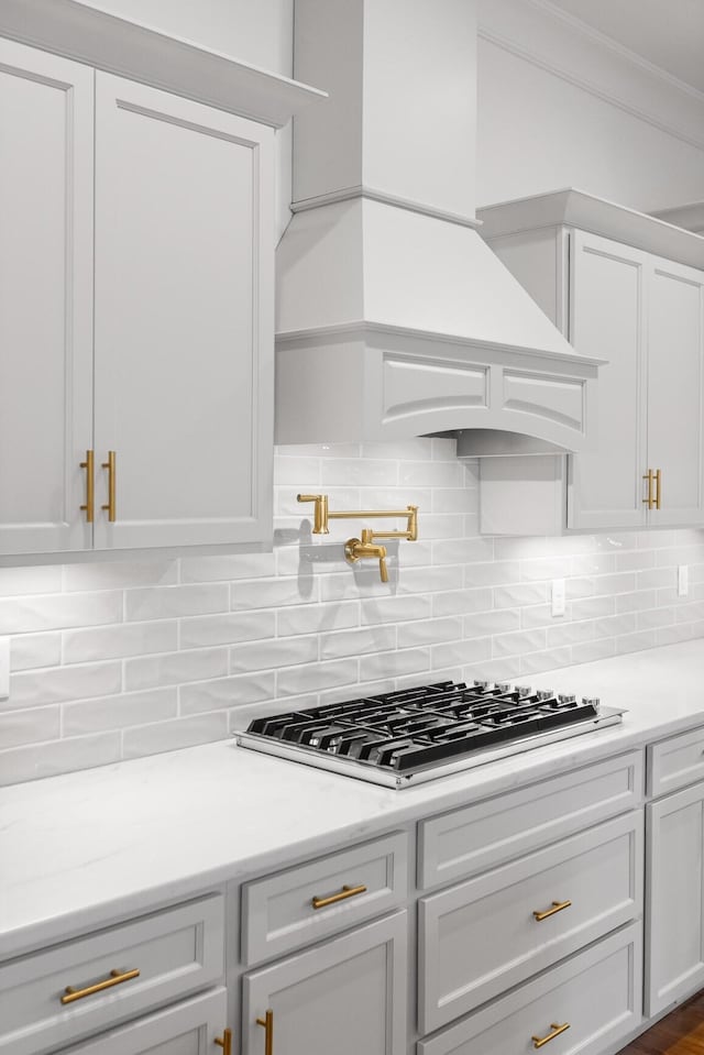 2208 Launcelot Rd, Chattanooga, TN 37421 - kitchen featuring stainless steel gas cooktop, white cabinets, light countertops, tasteful backsplash, and ornamental molding