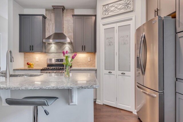 160 Majestic Ln, Pleasant View, TN 37146 - kitchen featuring stainless steel appliances, wall chimney range hood, a sink, light stone countertops, and a breakfast bar area