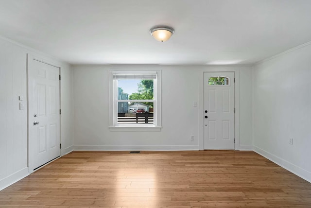 foyer with healthy amount of natural light, light wood-style flooring, ornamental molding, and baseboards