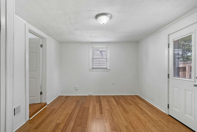 unfurnished room featuring a textured ceiling, light wood finished floors, crown molding, and baseboards