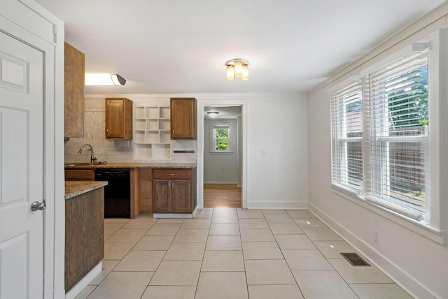 kitchen with black dishwasher, a sink, light tile patterned floors, brown cabinetry, and backsplash