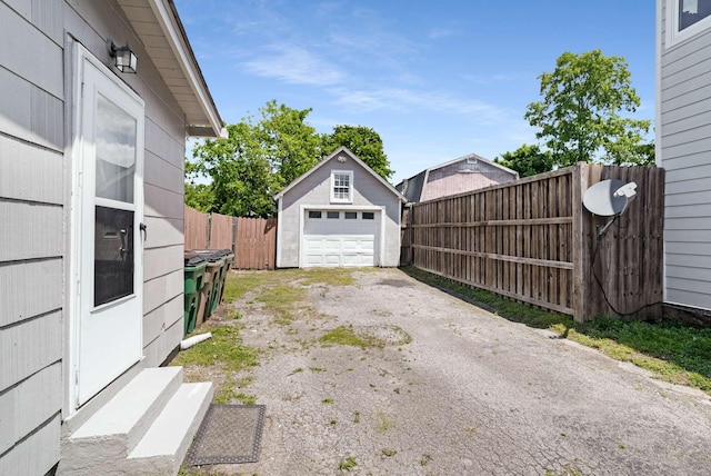 detached garage with asphalt driveway and fence