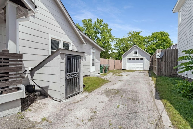 view of property exterior featuring a garage, asphalt driveway, an outbuilding, and fence