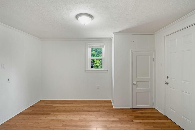 unfurnished room featuring light wood-type flooring, crown molding, a textured ceiling, and baseboards