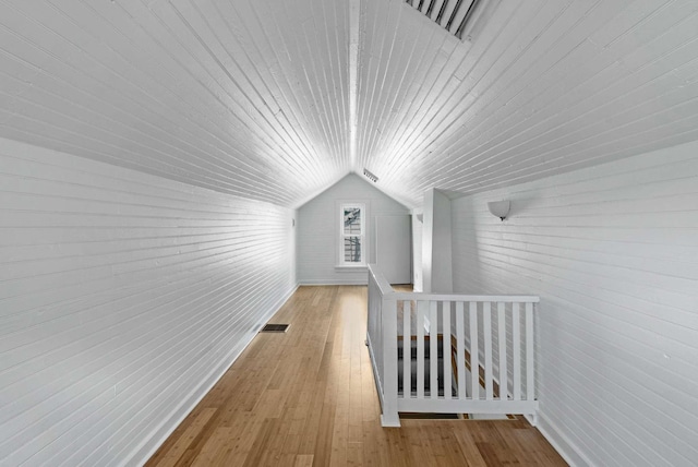 bonus room featuring wooden ceiling, lofted ceiling, hardwood / wood-style flooring, wooden walls, and brick wall