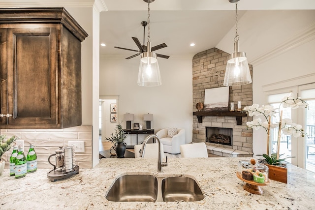 1219 Ben Forkum Dr, Lebanon, TN 37087 - kitchen featuring a sink, ornamental molding, dark brown cabinetry, backsplash, and a stone fireplace