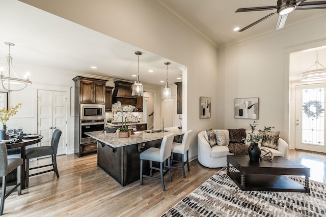 1219 Ben Forkum Dr, Lebanon, TN 37087 - kitchen featuring stainless steel appliances, a chandelier, dark brown cabinetry, a breakfast bar, and light wood-style flooring