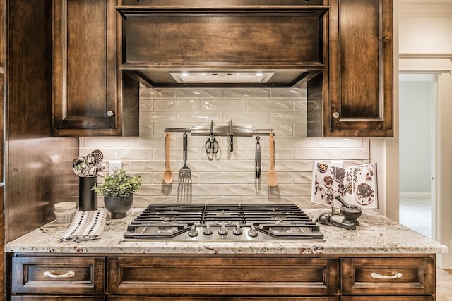 1219 Ben Forkum Dr, Lebanon, TN 37087 - kitchen with dark brown cabinets, stainless steel gas stovetop, decorative backsplash, and light stone counters