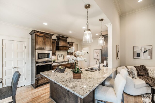 1219 Ben Forkum Dr, Lebanon, TN 37087 - kitchen featuring appliances with stainless steel finishes, a sink, dark brown cabinets, custom range hood, and a breakfast bar