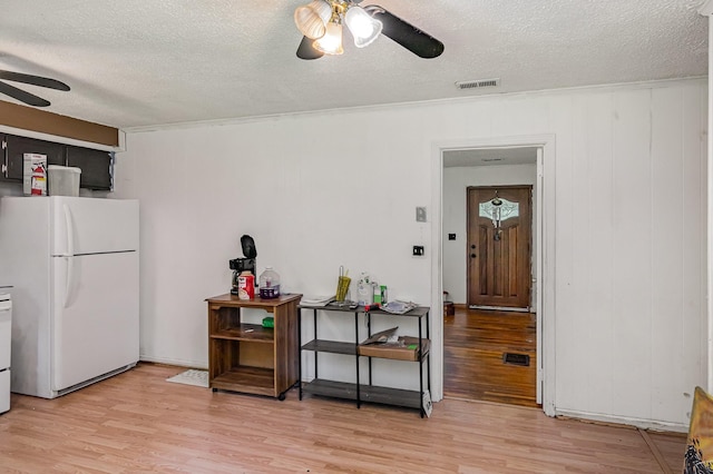 interior space featuring a ceiling fan, freestanding refrigerator, a textured ceiling, light wood finished floors, and stove