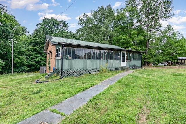 view of side of property with a sunroom, cooling unit, a yard, and entry steps