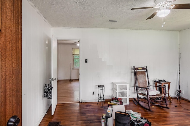 sitting room featuring wood finished floors, a ceiling fan, a textured ceiling, crown molding, and baseboards