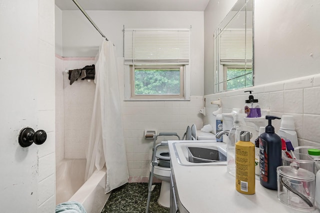full bath with tile walls, plenty of natural light, a sink, toilet, and shower / tub combo